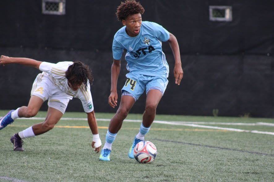Chaz L. Grey, wearing #74, dribbling toward the camera past a sliding defender